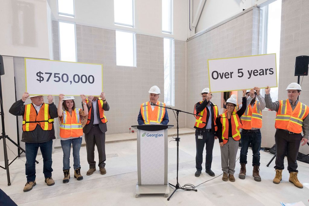 A group of people in safety vests and hard hats holding up two signs