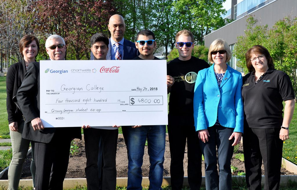 A group of people standing outside with a large cheque for $4,800.