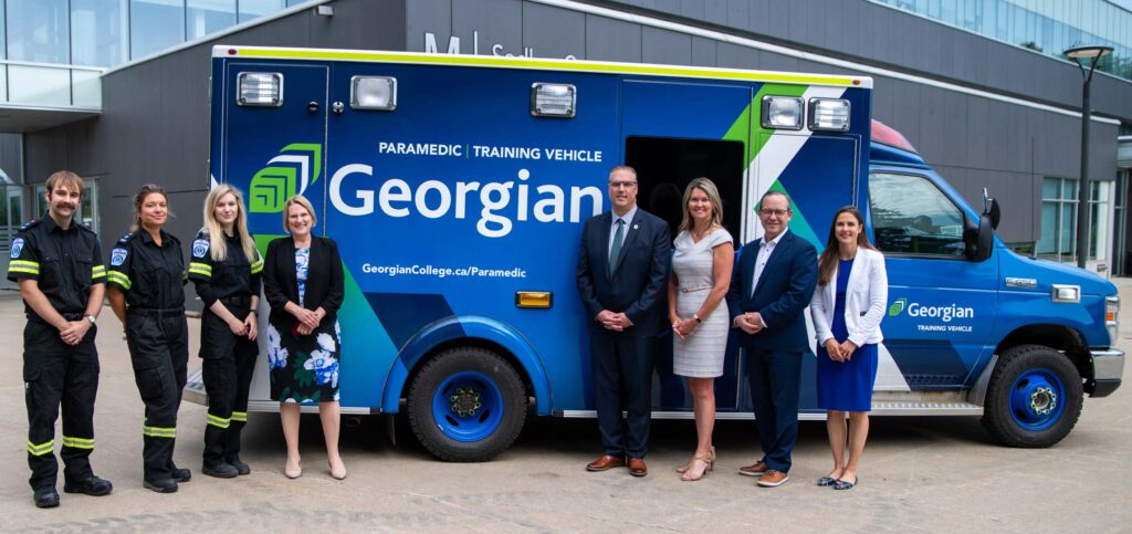 Eight people stand in front of an ambulance training vehicle at Georgian College.