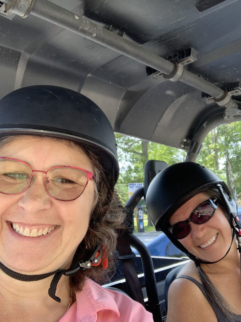 Two people wearing helmets and smiling 