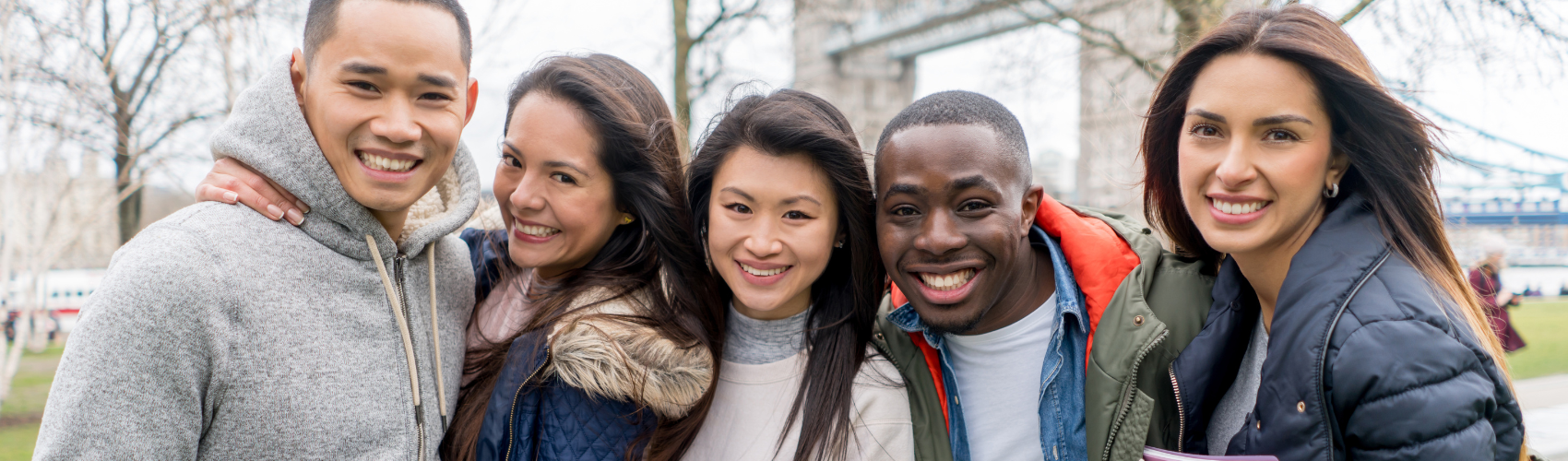 Group of students smiling and standing in front of London bridge.