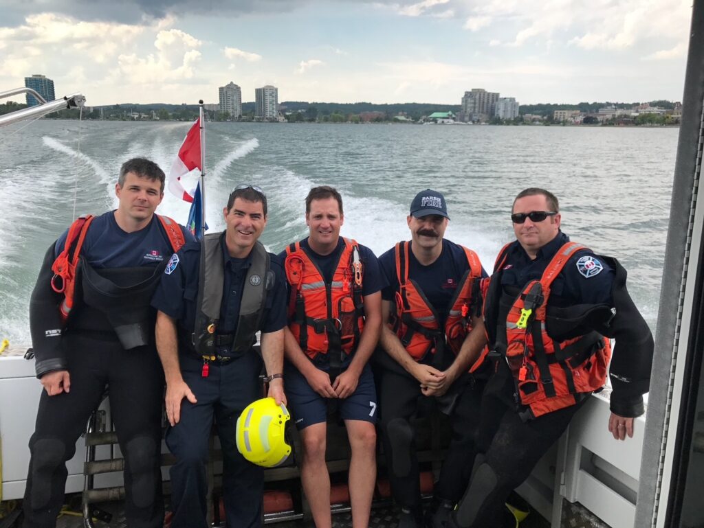 group of firefighters sitting in boat in gear.