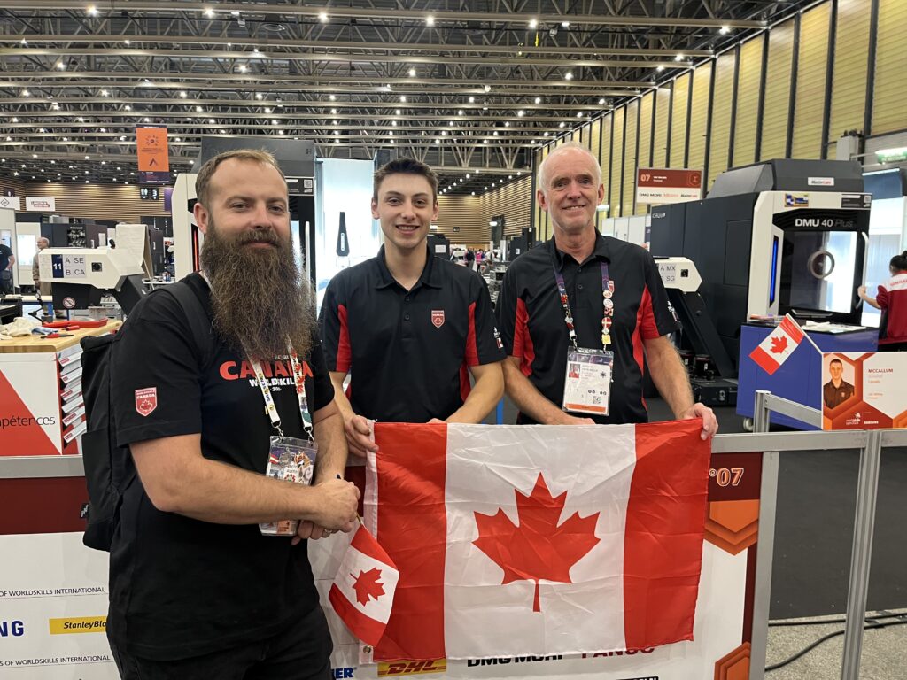 Ethan (middle) with mentors Brett Austin (left) and Jurgen Hierholzer (right) at Ethan's WorldSkills workstation. 