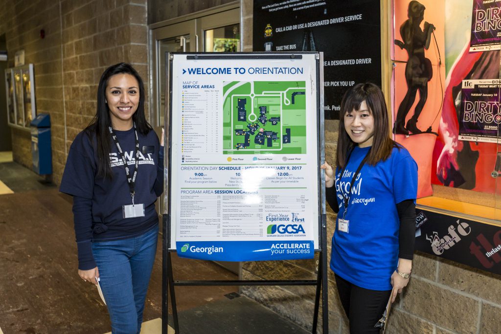 two female students volunteering at Orientation Day and welcoming new students to Georgian