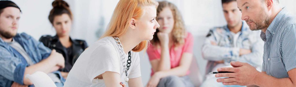 A counsellor provides guidance to a member in recovery at an addictions support group