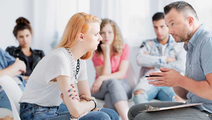 A counsellor provides guidance to a member in recovery at an addictions support group