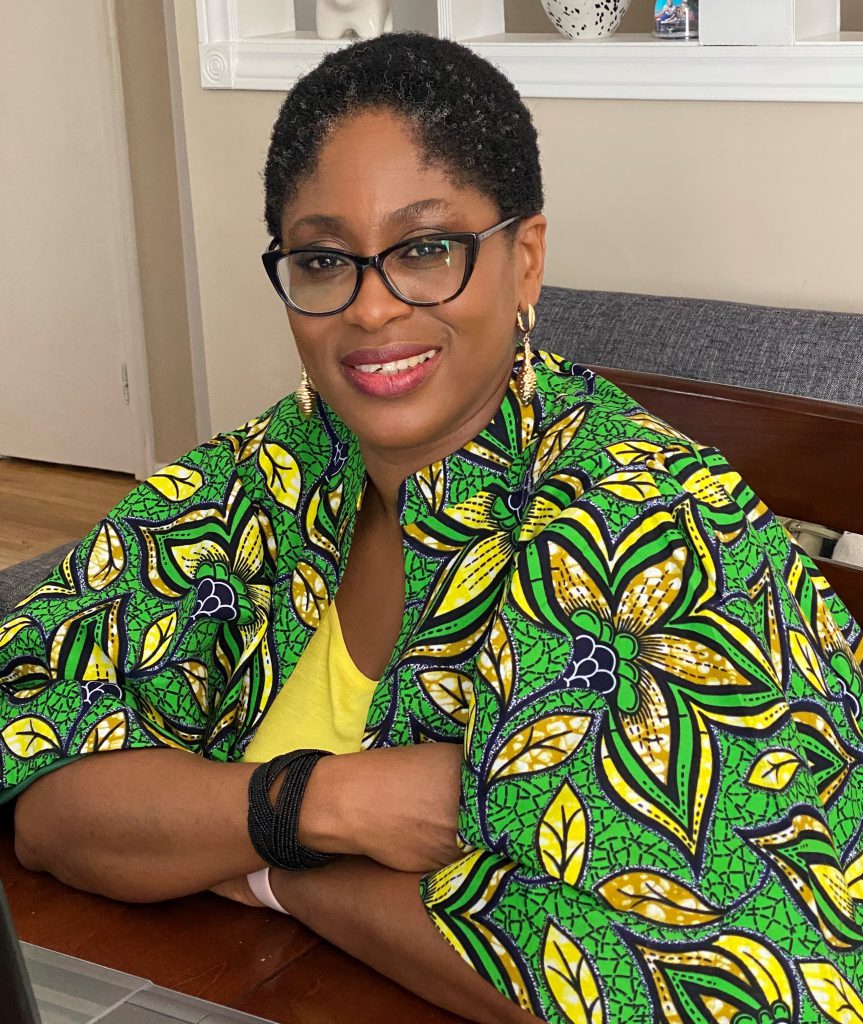 A person sits at a table and smiles at the camera.