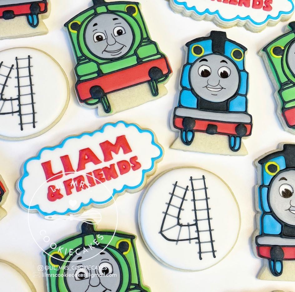Aerial view of sugar cookies decorated with trains and train tracks.