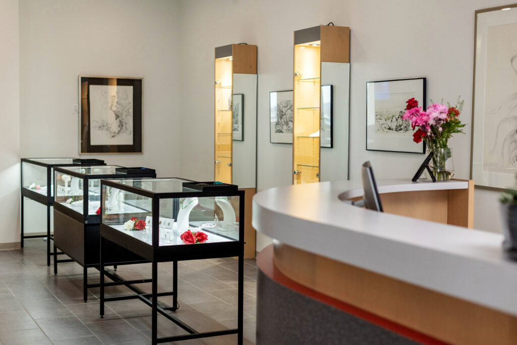 Inside Georgian Jewellery, an on-campus jewellery store at Georgian College. Displays with jewellery pieces, artwork hung on the walls, and a welcome desk with a flower vase.