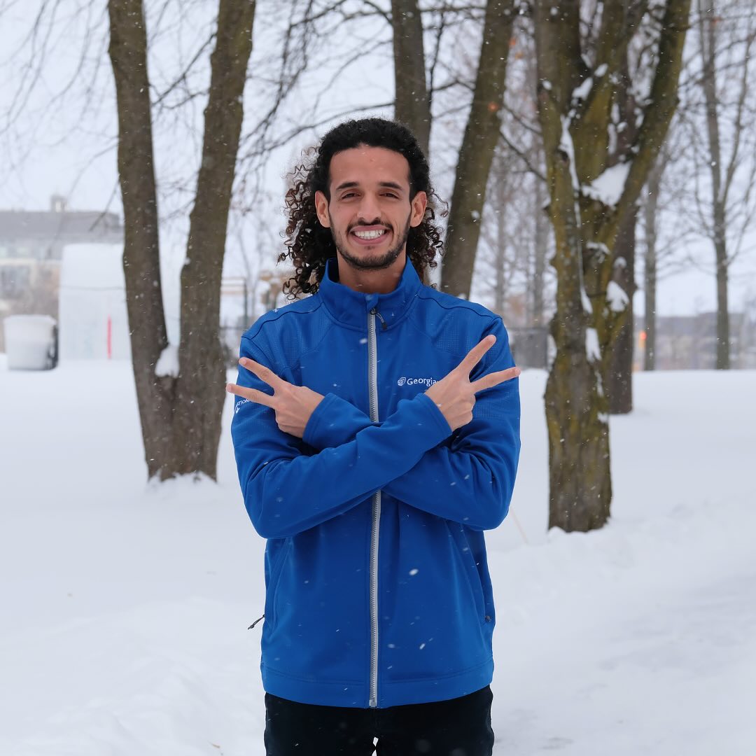 Georgian College student standing in the snow with a happy look on his face.