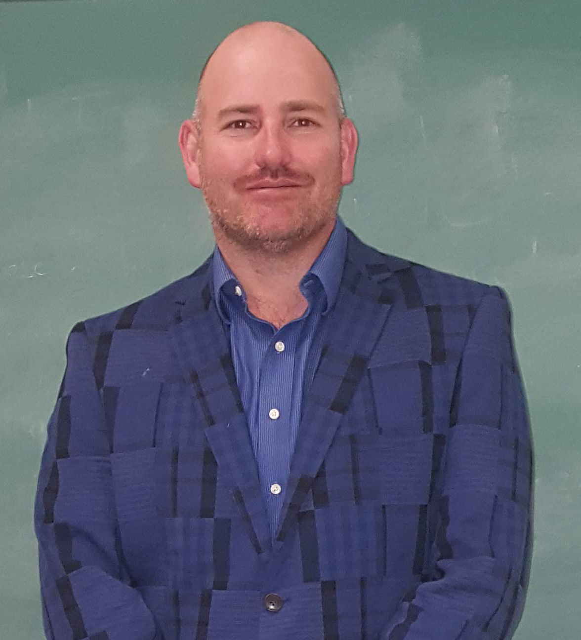 Brent Cotton with a blue suit in a dark green background