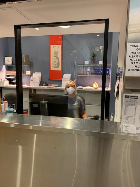 Customer Service Representative behind plexiglass barrier to stop the spread of COVID-19