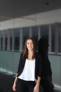 A smiling woman, leaning against a wall