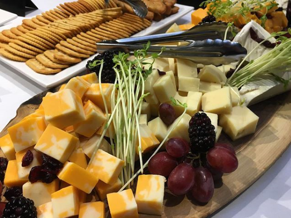 Assorted cheese, crackers, and grapes on a live-edge wooden board