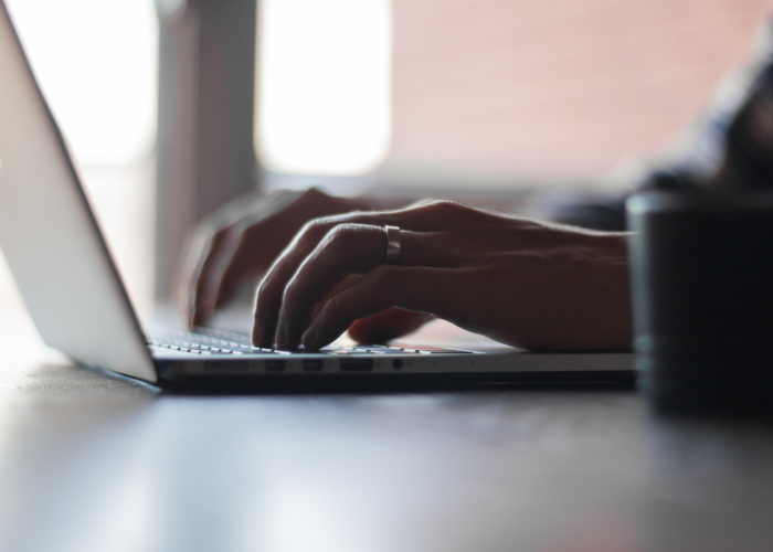 Hands typing on a laptop
