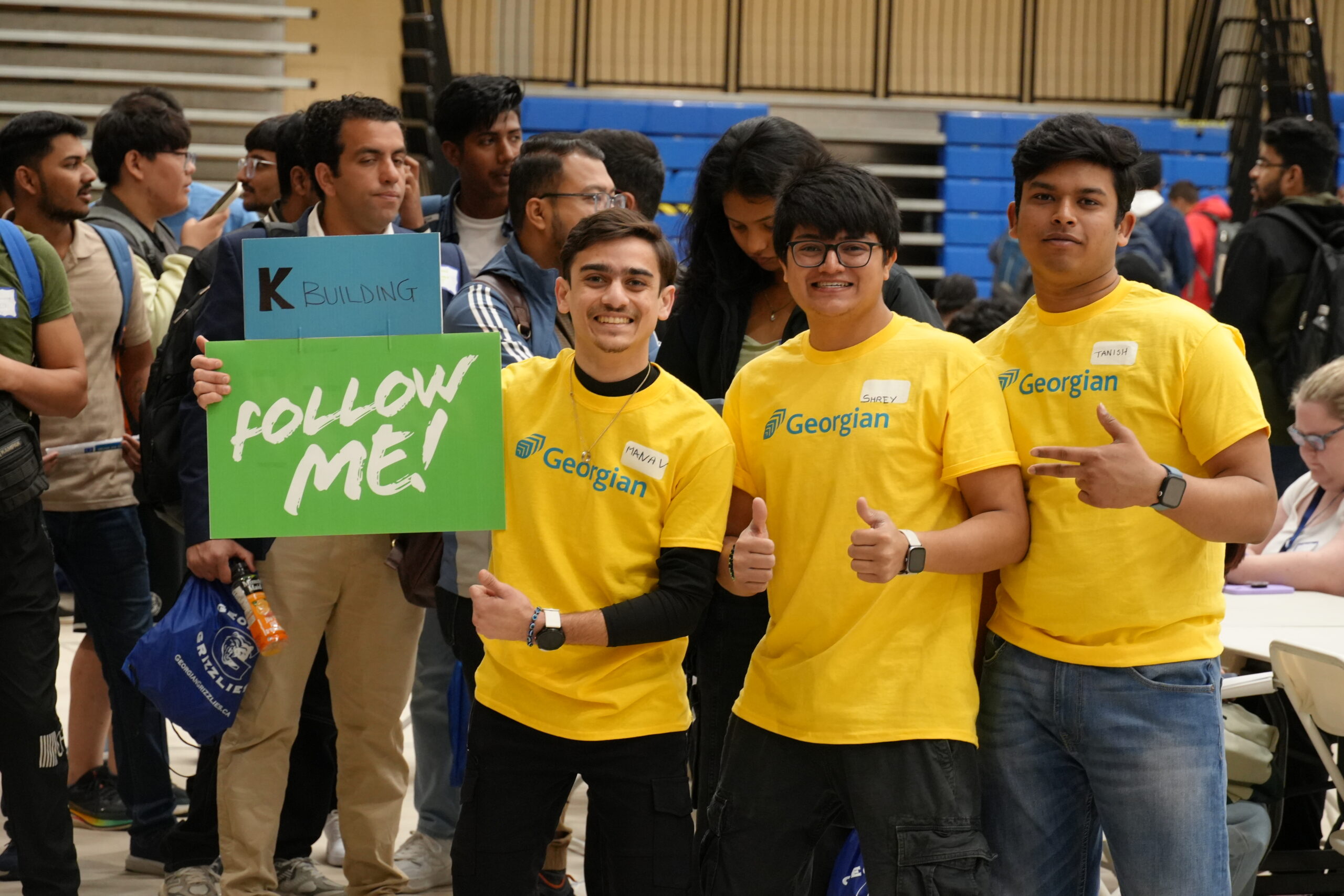 Students with sign saying 'follow me' waiting to go on campus tours.