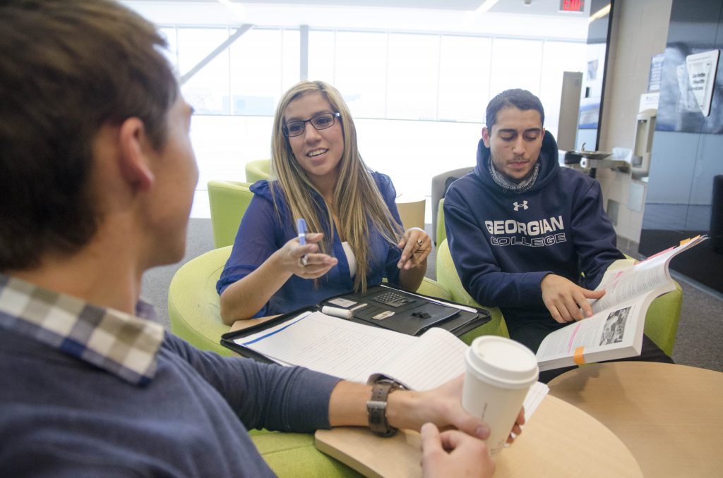 one female and two male students discussing course work in a student lounge in M building at the Barrie Campus