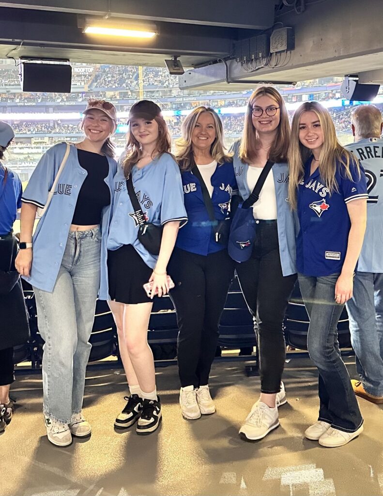 Five people wearing Toronto Blue Jays jerseys stand for a photo inside the Rogers Centre for a baseball game in Toronto.