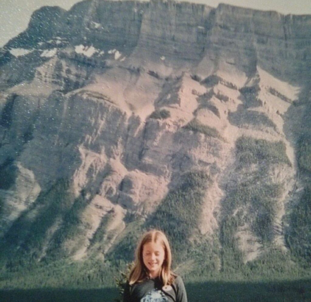 A young child standing in front of mountains.