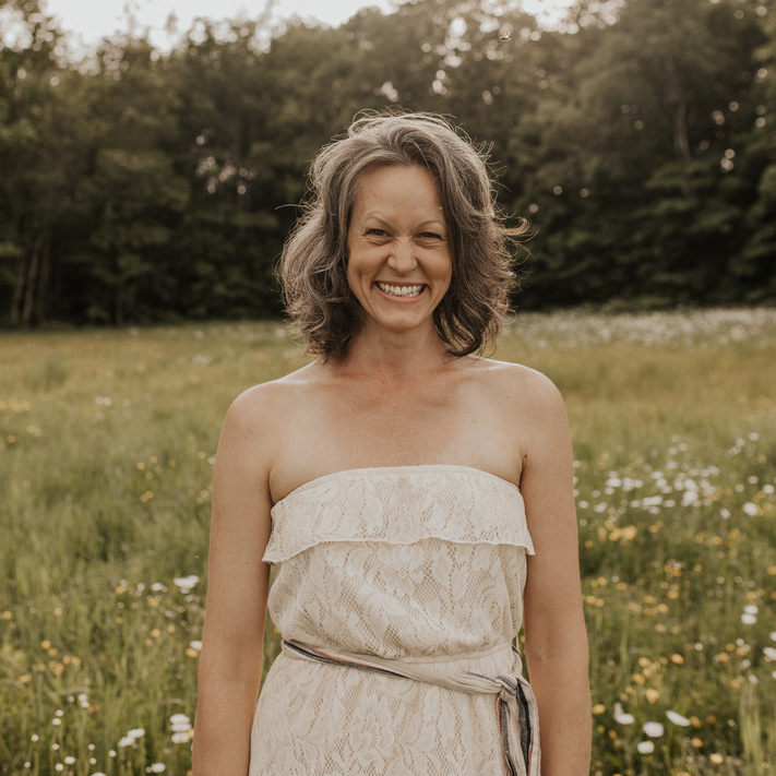 A woman wearing a white dress in a grass field
