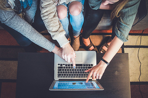 Group sitting together pointing at laptop screen