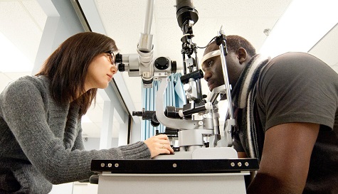 Georgian College Opticianry student uses optical equipment to test a client's eyesight