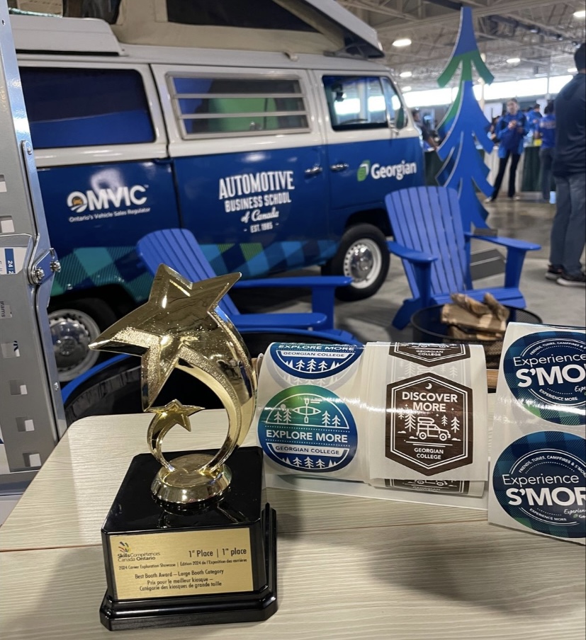 A trophy on a desk with stickers and a blue van in the background.