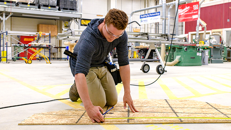 Georgian-Muskoka-construction-trades-pre-apprenticeship-student-Grant-Basso-measures-out-a-board-on-the-shop-floor