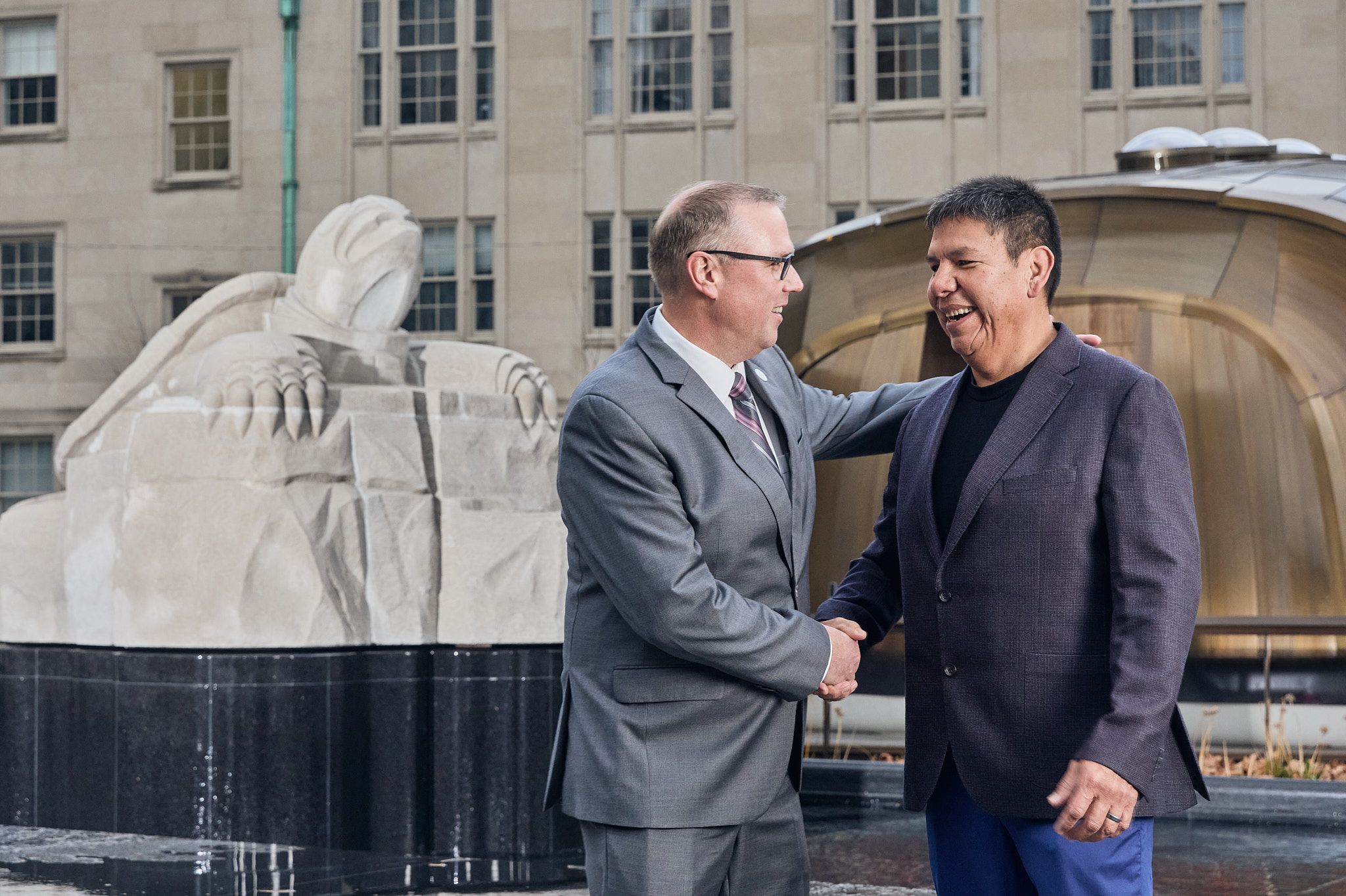 Georgian College President and CEO Kevin Weaver (left) shakes hands with Indigenous artist and Cabinetmaking Techniques alumnus Solomon King in front of King's turtle sculpture at Nathan Phillips Square in Toronto, Ontario, College. 