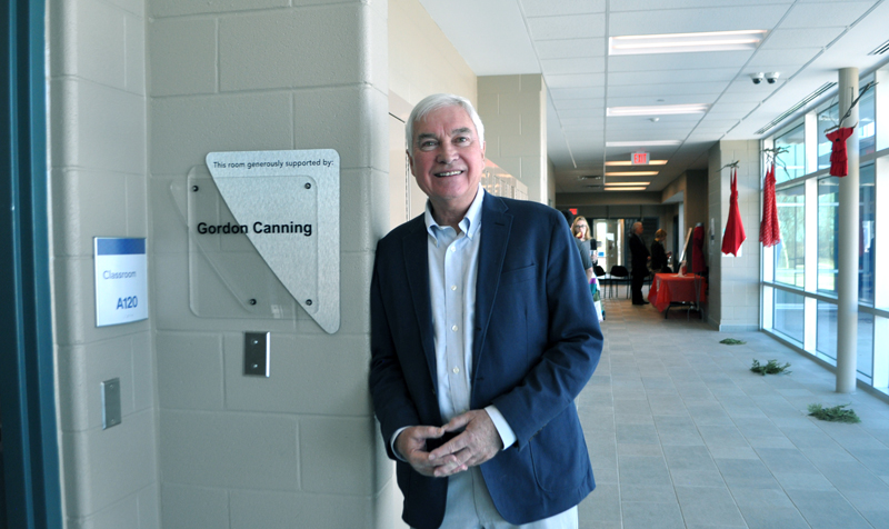 A well-dressed man stands in a hallway.