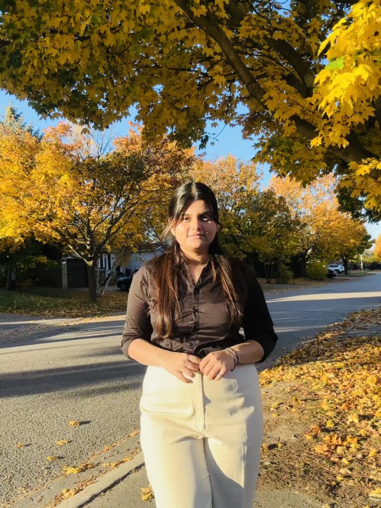 A student stands outside in front of trees.