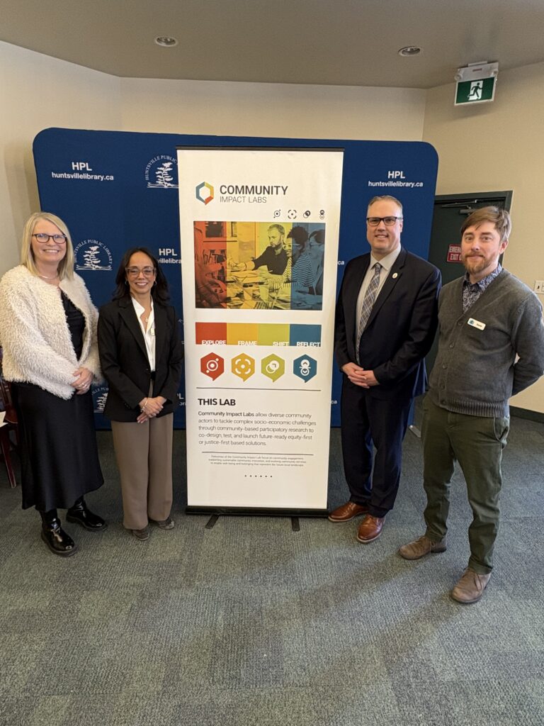 4 individuals standing in front of banner for community impact labs