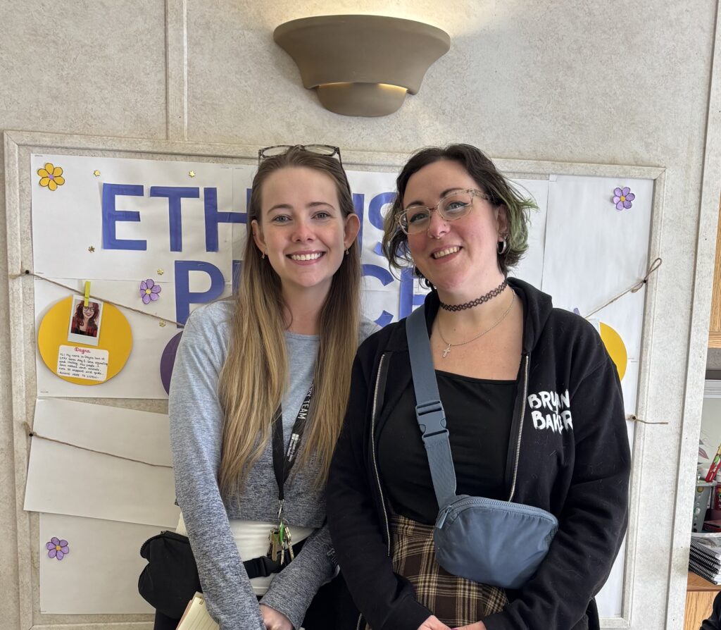 Two people smiling in front of a poster.