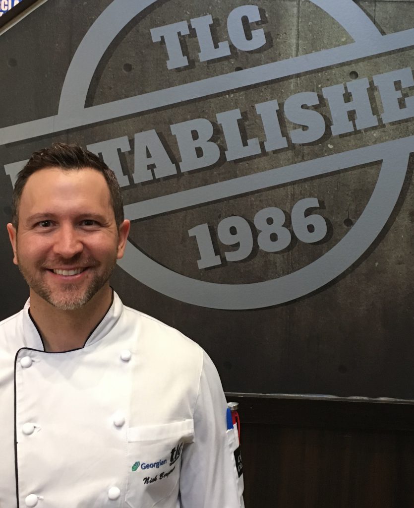 Photo of Nicholas Bergeron standing in front of a sign that says TLC established 1986