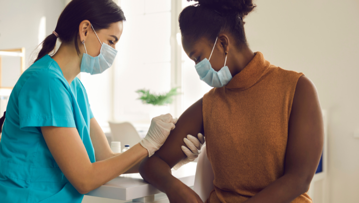 A medical professional cleaning a patient's arm to prepare them for immunization. 