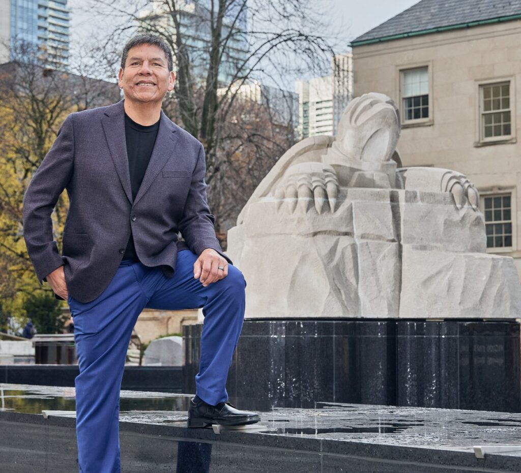 Indigenous artist and Cabinetmaking Techniques alumnus Solomon King stands outside in front of his turtle sculpture at Nathan Philips Square in Toronto, Ontario. Canada.