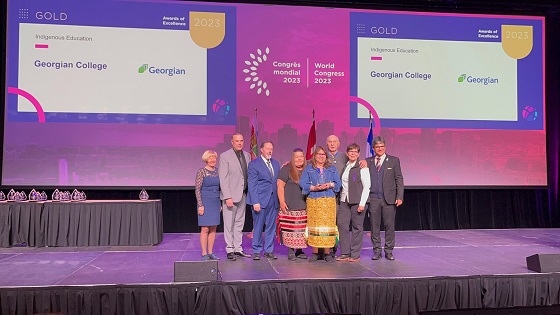 Group on stage receiving gold Indigenous Education Award