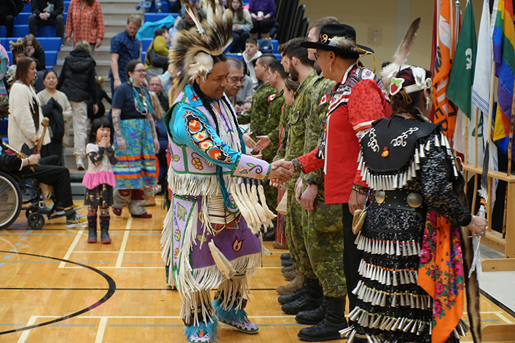 People dressed in Indigenous regalia shaking hands