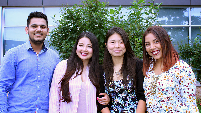 Four international students - one male and three females, standing outside.