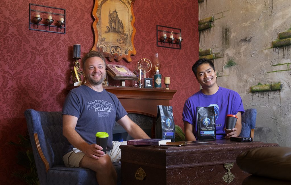 Two people sit at a table and smile at the camera.