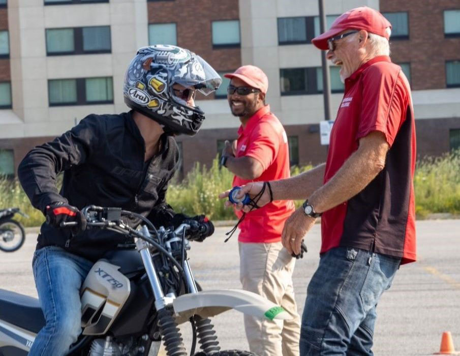 Instructor and student on motorcycle laughing.