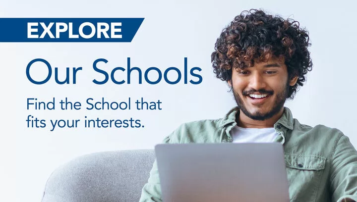 Curly haired man smiles at his laptop. "Explore Our Schools. Find the School that fits your interest."