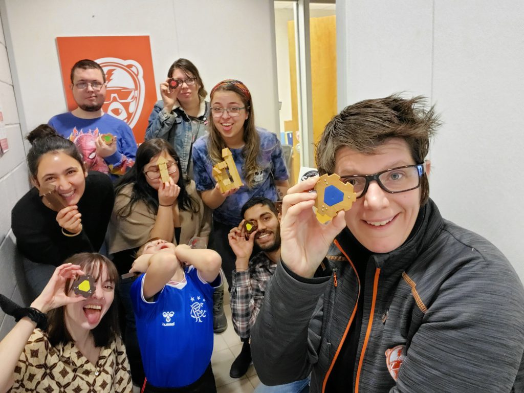 Person in forefront takes a selfie with a group of people behind them.