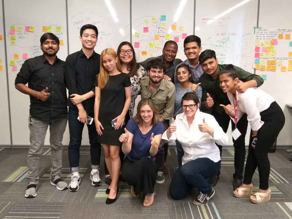 Group of people pose in front of a white board.