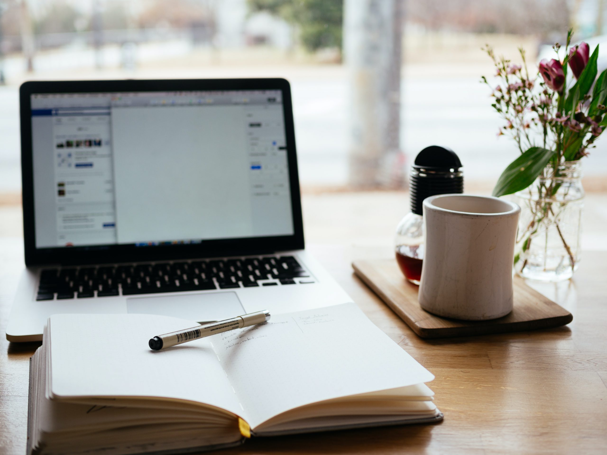 Desk with laptop, mug and book.