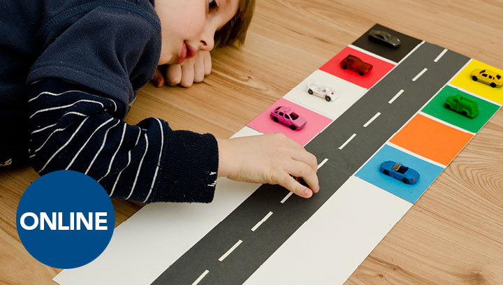 A young child laying on the ground next to a car parking toy mat