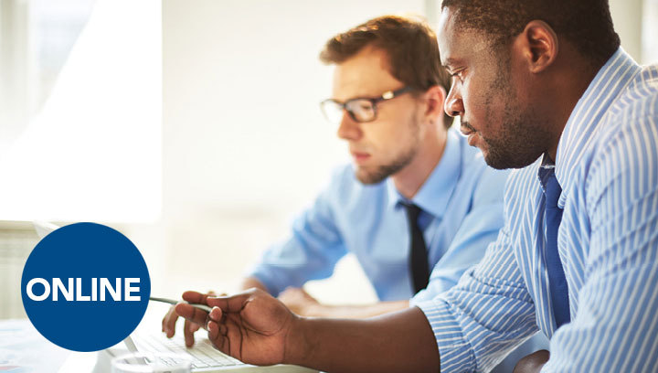 Two people in business attire looking at a laptop screen together