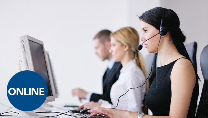 A group of people in business attire sitting at a computer desk, wearing headsets