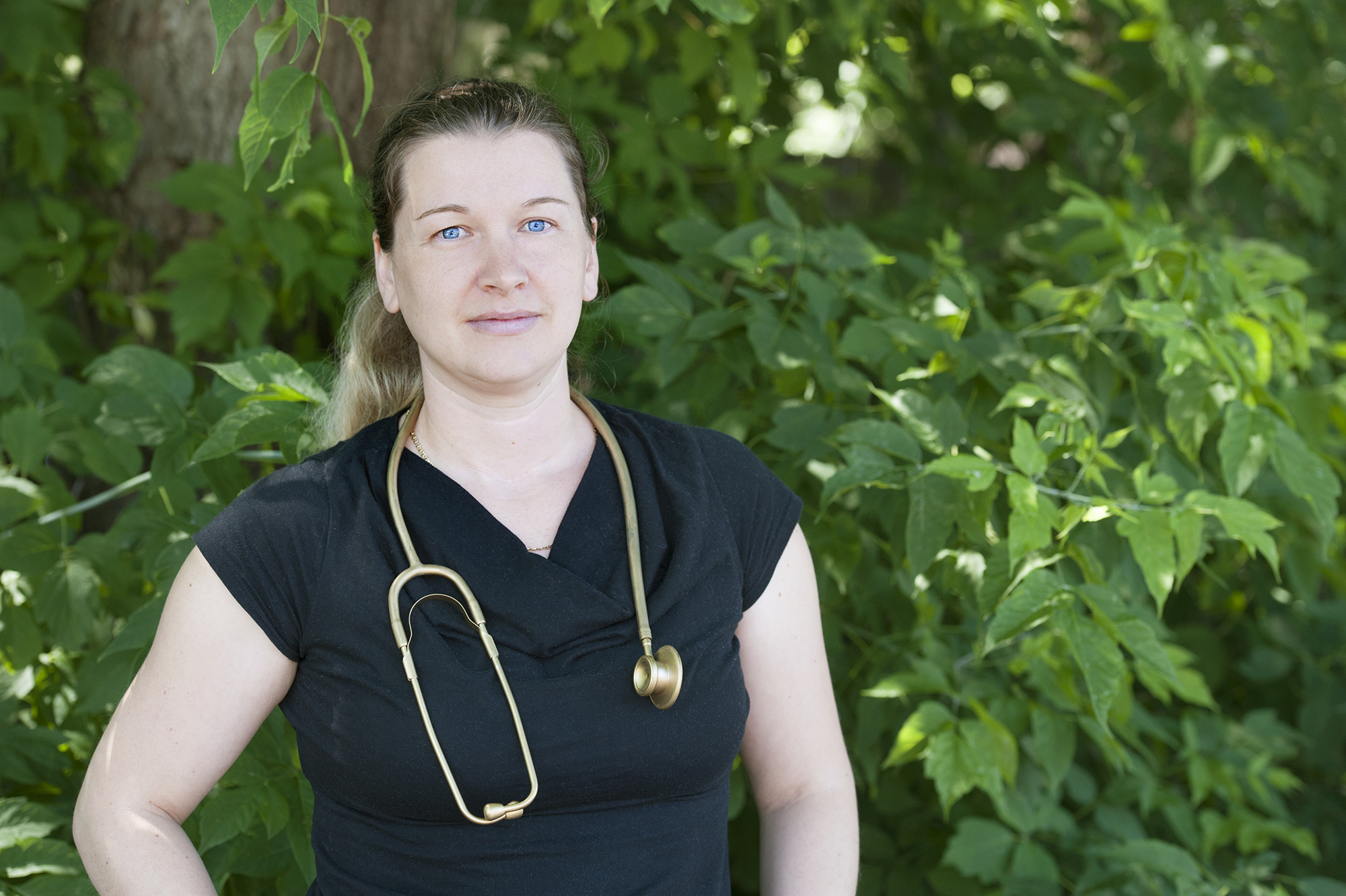 Part time Practical Nursing student Angela Tremblay looks at camera row of green trees in the background