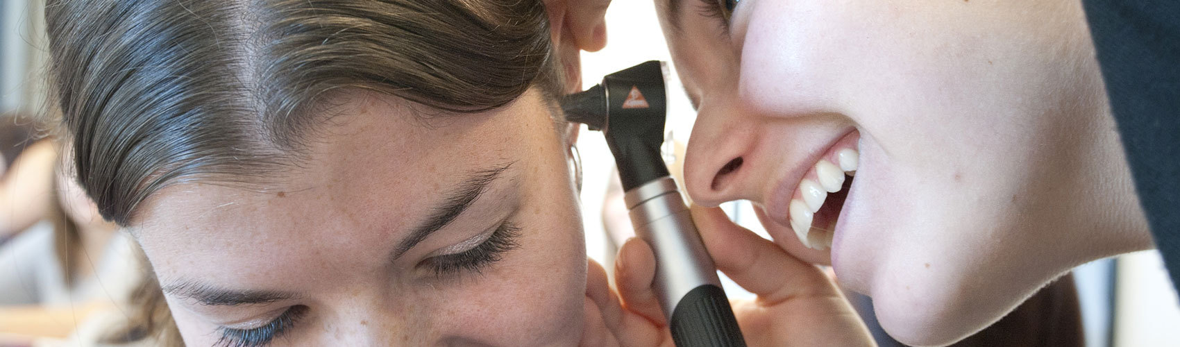 Student looking in someone's ear with an otoscope